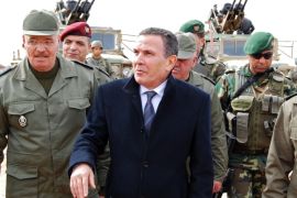 Tunisian Defense minister Farhat Horchani, center, with Chief of Staff of the Army Ismael Fathalli, left, attend a presentation of the anti-jihadi fence, in near Ben Guerdane, eastern Tunisia, close to the border with Libya, Saturday, Feb. 6, 2016. Tunisia's defense minister has visited an anti-jihadi fence that's being built on the country's border with Libya to stop Islamist militants from entering Tunisian territory. Defense Minister Farhat Horchani inspected the first completed part of the 196-kilometer (122-mile) fence Saturday, which aims to counter the threat from jihadi militants and render the entire border impassable by vehicles. Horchani said the project came about with financial assistance from Germany and the U.S. (AP Photo/Benjamin Wiacek)