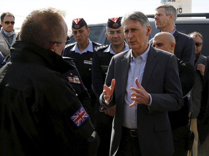 Britain's Foreign Secretary Philip Hammond (C) speaks with former British police officers, who are working with Jordanian police officers in a joint initiative to train and support the Community Police, in front of a mobile community police station, during his visit to Al Zaatari refugee camp in the Jordanian city of Mafraq, near the border with Syria, February 1, 2016. REUTERS/ Muhammad Hamed