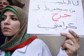 An Egyptian doctor holds an Arabic placard reading, "I'm the doctor, who will treat my dignity wound?" during a protest against rampant police abuses, after two doctors were beaten up by policemen in a Cairo hospital, in front of their headquarters of the Egyptian Medical Syndicate in Cairo, Egypt, Friday, Feb. 12, 2016. Doctors threatened to escalate if the government doesn’t hold police accountable for abuses. (AP Photo/Amr Nabil)