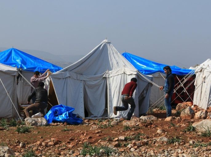 Internally displaced Syrians who fled from Aleppo construct a tent inside a refugee camp in the village of Batabo, northern Idlib countryside, Syria, February 14, 2016. REUTERS/Ammar Abdullah