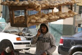 An employee of a bakery talks on his mobile while balancing on his head a tray of freshly baked bread from a local bakery in a street in Cairo, Egypt, January 12, 2016. REUTERS/Asmaa Waguih