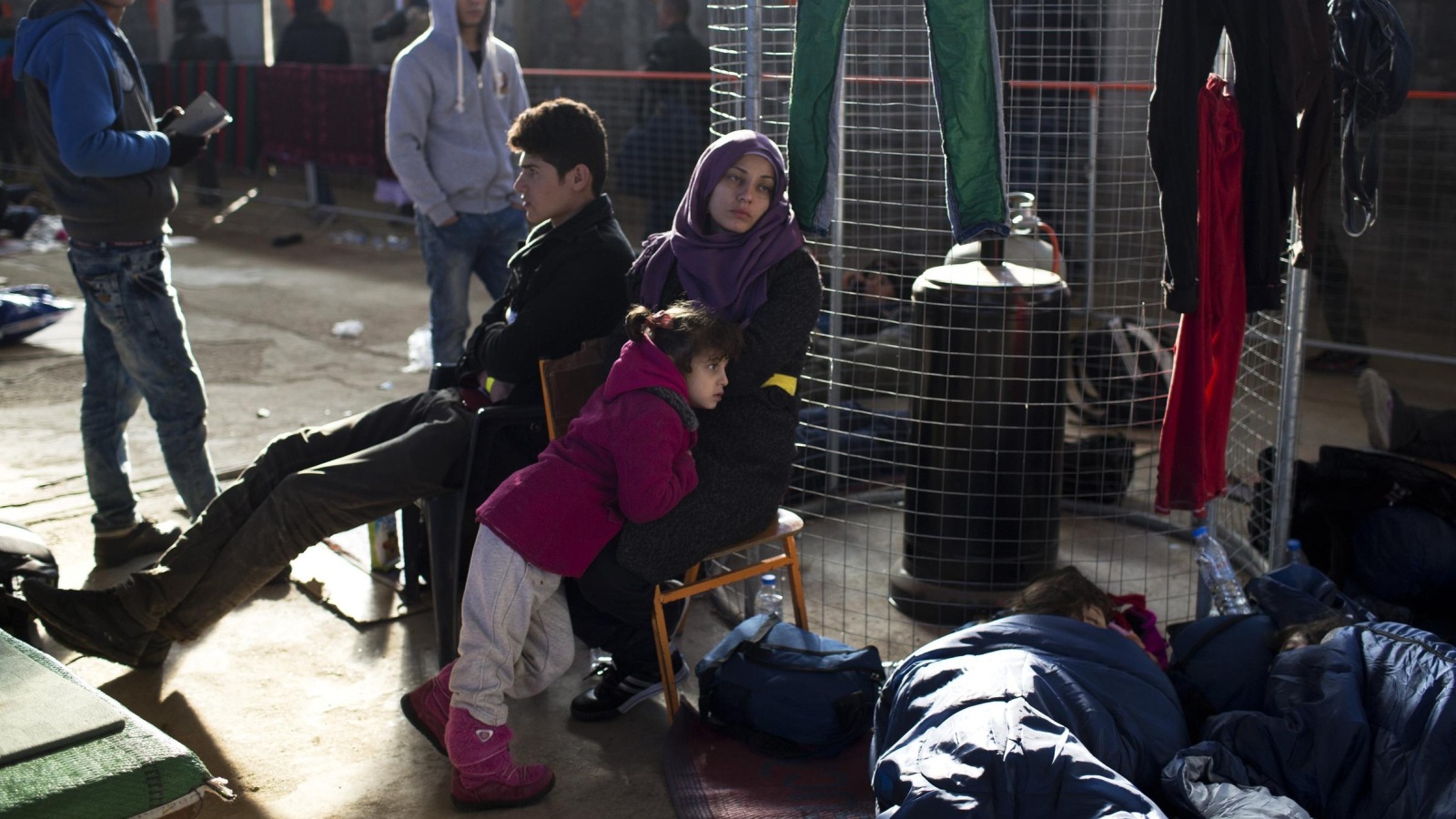 عائلة تنتظر دورها أمام مركز تسجيل اللاجئين بجزيرة خيوس اليونانية (أسوشيتد برس)