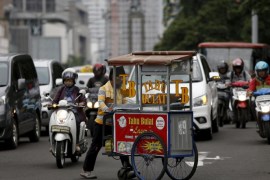 A vendor pushes his fried tofu cart across a busy street in Jakarta, Indonesia, February 11, 2016. Indonesia on Thursday opened dozens of sectors to foreign investors in what President Joko Widodo has described as a "Big Bang" liberalisation of its economy, Southeast Asia's largest. REUTERS/Darren Whiteside