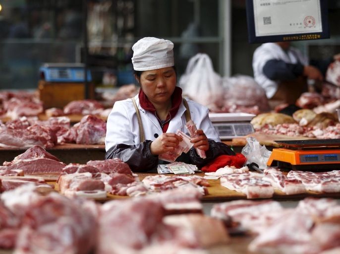A meat vendor arranges her yuan banknotes at her stall inside a food market in Kunming, Yunnan province, China, October 14, 2015. Consumer inflation in China eased more than expected in September while producer prices fell for the 43rd straight month, adding to concerns over growing deflationary pressures in the world's second-largest economy. REUTERS/Wong Campion