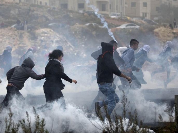Palestinian protesters run for cover from tear gas fired by Israeli soldiers during clashes, after the funerals of Ahmed Abu al-Aish, 28, and Laith Manasrah, 21, from Qalandia refugee camp, in the West Bank city of Ramallah, Monday, Nov. 16, 2015. Two Palestinians were killed and three wounded in clashes with Israeli troops early Monday in a Palestinian refugee camp in the Jerusalem area, a Palestinian health official said. (AP Photo/Majdi Mohammed)