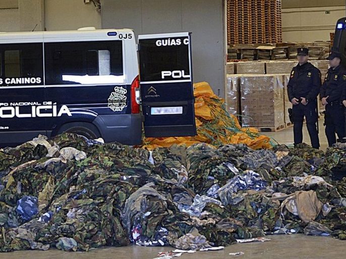 An undated handout photo released by the Spanish National Police Department on 04 March 2016 of policemen (R) standing guard next to some 20,000 uniforms and military accessories which were to be sent tothe Jihad organizations of Jabaht Al Nusra and ISIS, after a police operation in the Spanish ports of Valencia (east), and Cadiz (south). The National Police seized three containers and opened them last 07 February when seven people were arrested after being acussed of allegedly logistic and financial support of terrorist groups in Syria and Iraq. EPA/SPANISH NATIONAL POLICE/HANDOUT