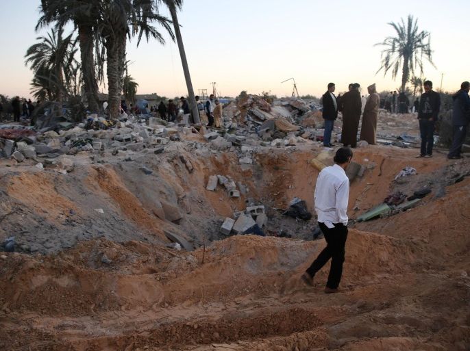 In this Friday, Feb. 19, 2016 photo, people gather after an air strike on a house and training camp belonging to the Islamic State group, west of Sabratha, Libya. American F-15E fighter-bombers struck an Islamic State militant training camp in rural Libya near the Tunisian border Friday, killing dozens, probably including an IS operative considered responsible for deadly attacks in Tunisia last year, U.S. and local officials said. (AP Photo/Mohamed Ben Khalifa)