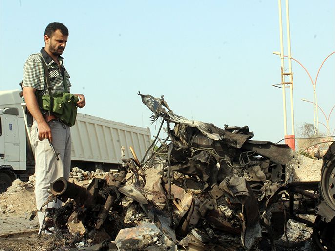 epa05231432 A Yemeni inspects the site of suicide car bombings targeting security checkpoints in the southern port city of Aden, Yemen, 26 March 2016. According to reports, three suicide bombings struck security checkpoints in the Yemeni city of Aden, killing at least 22 people. The so called Islamic State (IS) claimed responsibility for the attacks. EPA/STR