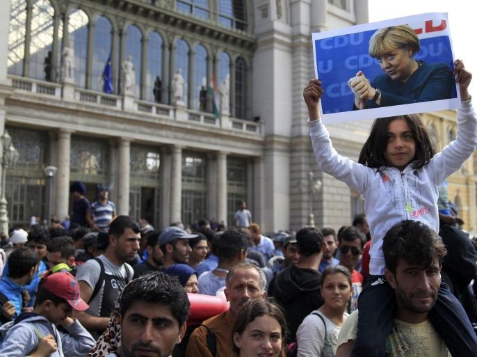 File photo of a young girl holding up a picture of German Chancellor Angela Merkel as migrants set off on foot for the border with Austria from outside Keleti station in Budapest, Hungary, September 4, 2015. Time magazine named German Chancellor Angela Merkel its 2015 "Person of the Year" on December 9, 2015, noting her resilience and leadership when faced with the Syrian refugee crisis and turmoil in the European Union over its currency this year. REUTERS/Bernadett Szabo/Files