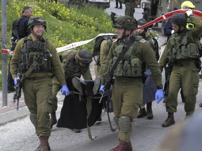 Israeli soldiers carry the body of one of two Palestinian who were killed after a stabbing attack in Hebron, West Bank, Thursday, March 24, 2016. The Israeli military has detained a soldier who was captured on video shooting an injured Palestinian lying on the ground. The army says the incident took place in the West Bank city of Hebron after two Palestinians stabbed and wounded an Israeli soldier. (AP Photo)