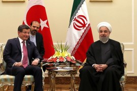 In this photo released by an official website of the office of the Iranian Presidency, President Hassan Rouhani, right, meets with Turkish Prime Minister Ahmet Davutoglu under portraits of the late Iranian revolutionary founder Ayatollah Khomeini, left, and Supreme Leader Ayatollah Ali Khamenei, at his office in Tehran, Iran, Saturday, March 5, 2016. An unidentified interpreter sits in background. (Iranian Presidency Office via AP)