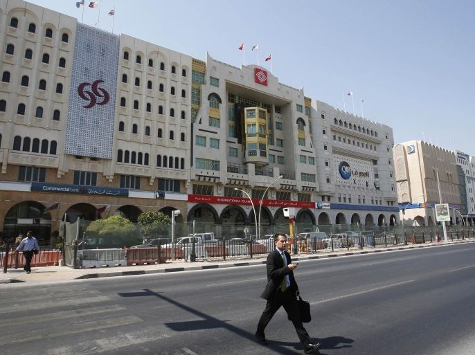 A man crosses the Grand Hamad street that hosts banks and financial institutions in Doha in this October 9, 2012 file photo. The year 2012 was transformational for global banks in the Middle East. Faced with a sharp slump in regional deal activity and pressure to save money, they reassessed their business models in a region that was once expected to become a key market for them, because of its oil and its sovereign wealth funds. To match story MIDEAST-BANKS/STRATEGY REUTERS/Fadi Al-Assaad/Files (QATAR - Tags: BUSINESS)