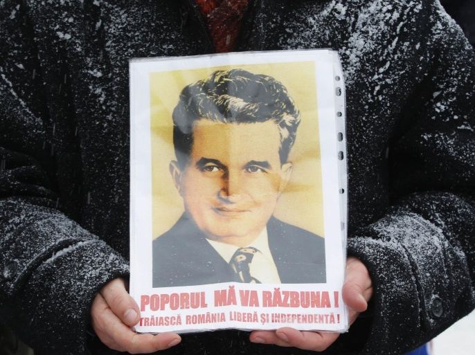 A man holds a portrait of Romania's late communist dictator Nicolae Ceausescu at his grave in a Bucharest cemetery January 26, 2013, which would have been his 95th birthday. Year after year nostalgic Communists gather to mourn Ceausescu, who was executed on Christmas Day together with his wife Elena in 1989, following a popular uprising. The poster reads: "People will avenge me! Long live free and independent Romania". REUTERS/Bogdan Cristel (ROMANIA - Tags: POLITICS ANNIVERSARY)