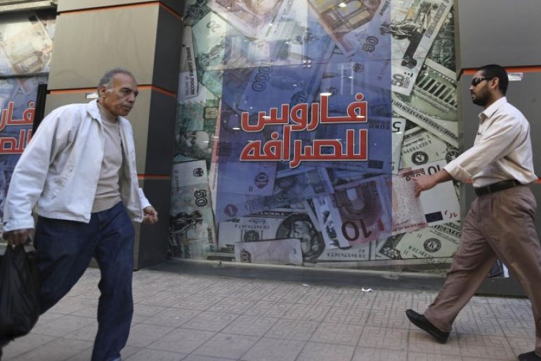 People walks outside an exchange bureau in Cairo , March 12, 2015. After four years of political turmoil, Egypt is staking its economic revival on an investment summit in Sharm el-Sheikh it hopes will burnish its image and attract billions of dollars. REUTERS/Mohamed Abd El Ghany (EGYPT - Tags: POLITICS BUSINESS)