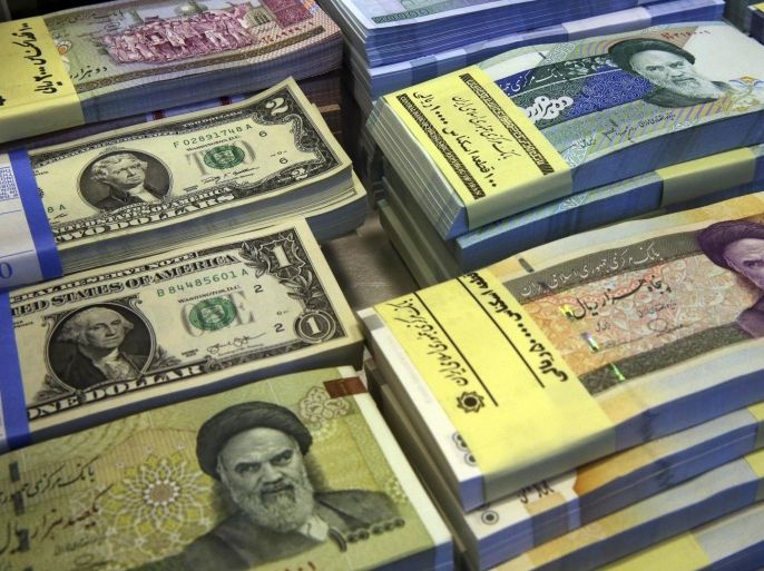 FILE--In this Saturday, April 4, 2015 file photo, Iranian and U.S. banknotes are on display at a currency exchange shop in downtown Tehran, Iran. Iran said Tuesday, Jan. 19, 2016, it successfully transferred some of the billions of dollars' worth of frozen overseas assets following the implementation of the nuclear deal with world powers. But ordinary Iranians are still waiting to see how their daily lives will improve and how fast Iranian companies will gain access to financial markets worldwide. (AP Photo/Vahid Salemi,File)
