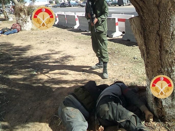 This photo taken Monday, Match 7, 2016 and provided by the Tunisian Defense Ministry on Tuesday, March 8, 2016 shows a soldier standing guard near the lifeless bodies of militants killed during fighting with Tunisian forces in the city of Ben Guerdane, southern Tunisia. The death toll from clashes between Tunisian forces and extremist attackers near the Libyan border has risen to 55, including 36 attackers, Tunisian Prime Minister Habid Essid said Tuesday. (Tunisian Defense Ministry via AP)