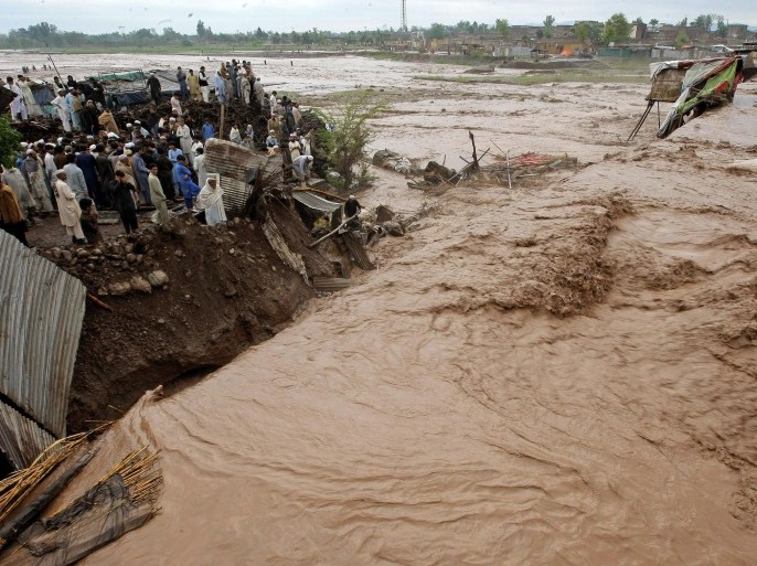 Pakistani villagers watch at flash flooding on the outskirts of Peshawar, Pakistan, Sunday, April 3, 2016. A Pakistani national disaster management official says flash floods triggered by torrential rains have killed dozens of people in the country's northwest. (AP Photo/Mohammad Sajjad)