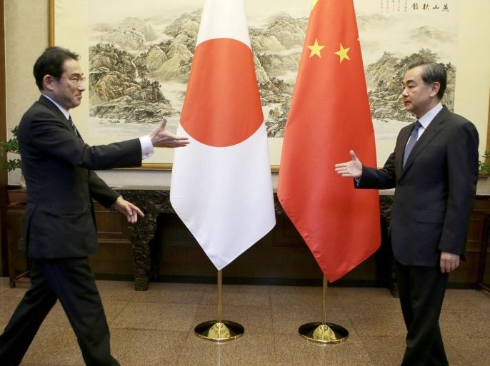 Japanese Foreign Minister Fumio Kishida (L) and China's Foreign Minister Wang Yi stretch to shake hands during a meeting at Diaoyutai State Guesthouse, in Beijing, China, 30 April 2016.