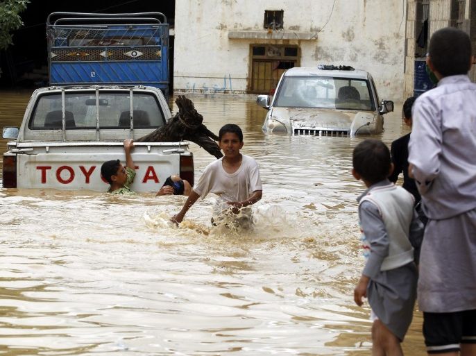 Yemenis walk near flooded cars following heavy rains in the northern city of Amran, Yemen, 14 April 2016. According to reports, at least 16 people have been died in a flash flood triggered by heavy rains in several Yemeni provinces on the same day.