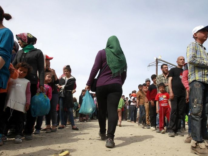 Women, migrants and refugees, left, and men, right, wait in lines for food packages provided by humanitarian workers in a makeshift camp at the northern Greek border station of Idomeni, Friday, April 1, 2016. Some 11,500 remain camped out at the border with Macedonia, ignoring instructions from the Greek government to move to organized shelters. (AP Photo/Boris Grdanoski)