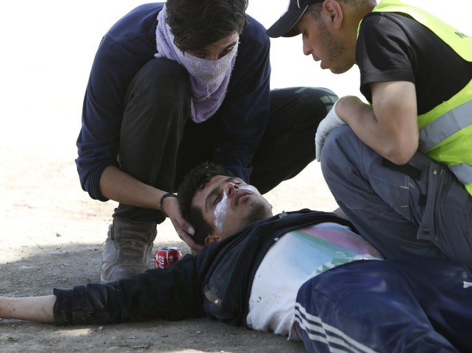 Migrants assist a wounded man after a protest at the northern Greek border point of Idomeni, Greece, Sunday, April 10, 2016. Migrants have clashed with Macedonian police after trying to scale the fence separating Greece from Macedonia in the border town Idomeni. Macedonian police used tear gas and they responded by throwing rocks at the police. (AP Photo/Amel Emric)