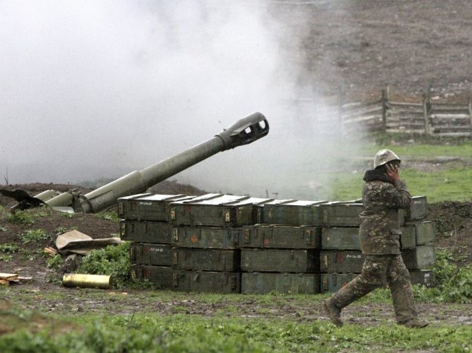 An Armenian covers his ears while a howitzer fires at an artillery position of the self-defense army of Nagorno-Karabakh near Martakert, Azerbaijan, Sunday, April 3, 2016. Azerbaijan's Defense Ministry announced a unilateral cease-fire Sunday against the separatist region of Nagorno-Karabakh, but rebel forces in the area said that they continued to come under fire from Azerbaijani forces. (Vahram Baghdasaryan, PHOTOLURE via AP)