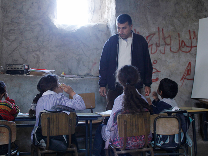‪‬ عبد اللطيف خطاطبة أستاذ القرية يدرس تلاميذه بالمسجد بعد هدم الاحتلال للمدرسة (الجزيرة)