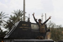 A member of Iraq's elite counterterrorism forces flashes the victory sign after entering the downtown of Hit, west of Baghdad, Iraq, Thursday, April 7, 2016. As they advanced on the Islamic State-held town of Hit, Iraqi counterterrorism troops had to decide how to press the attack. If they stormed in with armor and airstrikes, they risked heavy casualties and might allow the militants to flee. (AP Photo/Osama Sami)