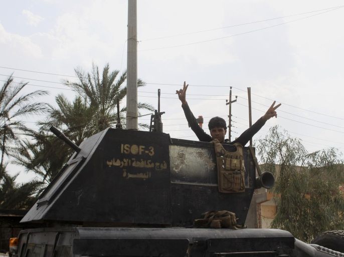 A member of Iraq's elite counterterrorism forces flashes the victory sign after entering the downtown of Hit, west of Baghdad, Iraq, Thursday, April 7, 2016. As they advanced on the Islamic State-held town of Hit, Iraqi counterterrorism troops had to decide how to press the attack. If they stormed in with armor and airstrikes, they risked heavy casualties and might allow the militants to flee. (AP Photo/Osama Sami)