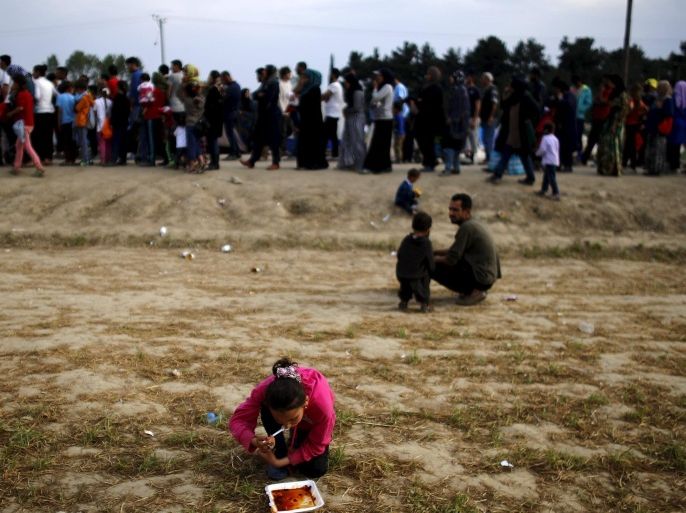 A girl eats on the ground as people line up for food at a makeshift camp for migrants and refugees at the Greek-Macedonian border near the village of Idomeni, Greece, April 8, 2016. REUTERS/Stoyan Nenov TPX IMAGES OF THE DAY