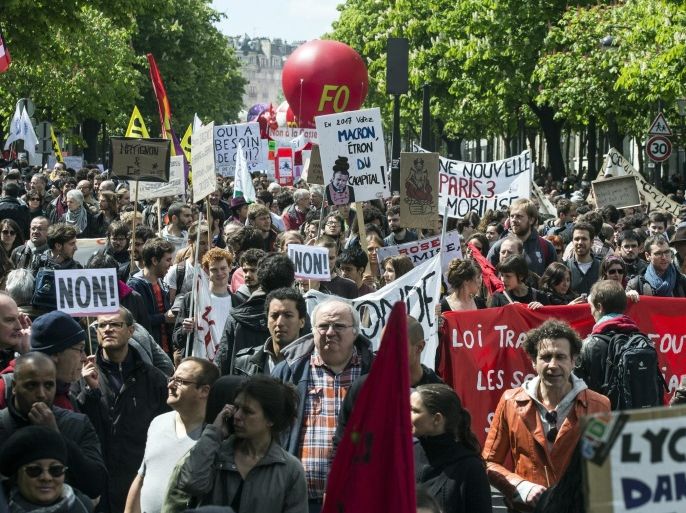Thousands of people protest against labor reform in Paris, France, 28 April 2016. In the back, a man holds a poster stating 'In 2017 vote for Macron the dejection of the capital'. Students, workers, seniors gave gathered today for the fourth general protest against French labor reform project.