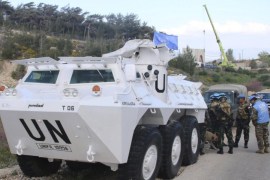 U.N. peacekeepers of the United Nations Interim Force in Lebanon (UNIFIL) stand near their armored vehicle in Adaisseh village, in southern Lebanon as an Israeli crane is seen in the background operating along the Lebanese-Israeli borders, March 21, 2016. REUTERS/Karamallah Daher
