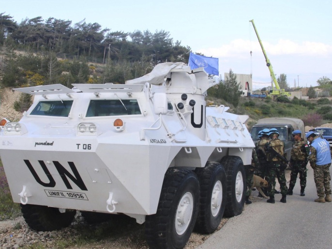 U.N. peacekeepers of the United Nations Interim Force in Lebanon (UNIFIL) stand near their armored vehicle in Adaisseh village, in southern Lebanon as an Israeli crane is seen in the background operating along the Lebanese-Israeli borders, March 21, 2016. REUTERS/Karamallah Daher