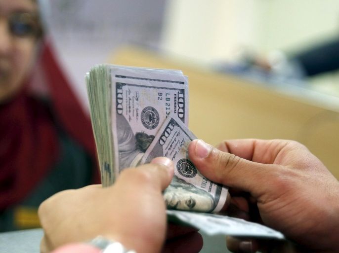 A customer counts his U.S. dollar money in a bank in Cairo, Egypt March 10, 2016. Egypt's central bank devalued the pound currency on Monday to 8.85 pounds per dollar from 7.73, aiming to eliminate a black market for dollars that has flourished as a foreign exchange shortage stifles business activity. Picture taken March 10, 2016. REUTERS/Amr Abdallah Dalsh