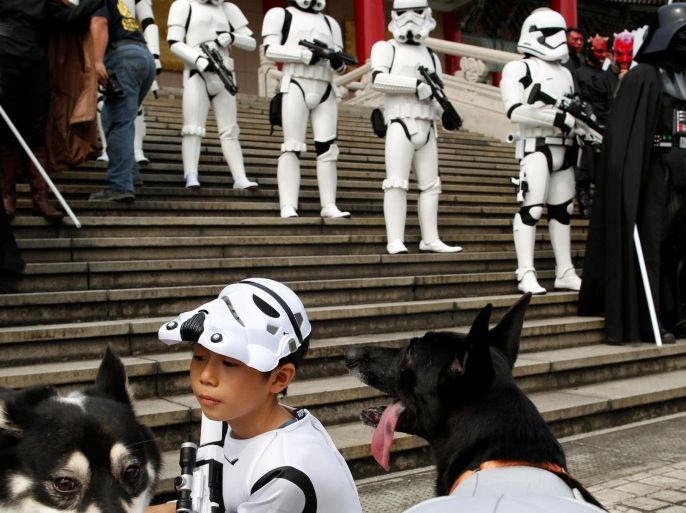 A child dressed as a Storm Trooper from "Star Wars" plays with dogs during Star Wars Day in Taipei, Taiwan, May 4, 2016. REUTERS/Tyrone Siu