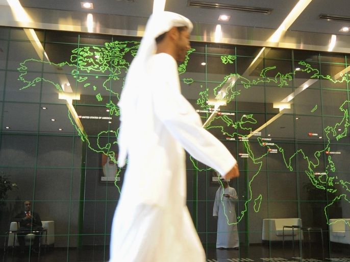 An employee walks past a screen displaying the worldwide locations of the National Bank of Abu Dhabi, at the bank's headquarters in Abu Dhabi, in this April 3, 2013 file photo. There is a growing list of banks in the Gulf Arab region which, flush with liquidity and backed by sound capital bases, are reviving mergers and acquisitions in the financial sector - an industry which until last year had seen little action since the 2008 credit crisis. Banks, such as National B