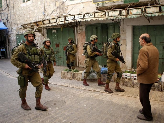 Israeli soldiers on patrol in front of Palestinians in the Old City in the Old City of Hebron on the West Bank, 08 May 2016.