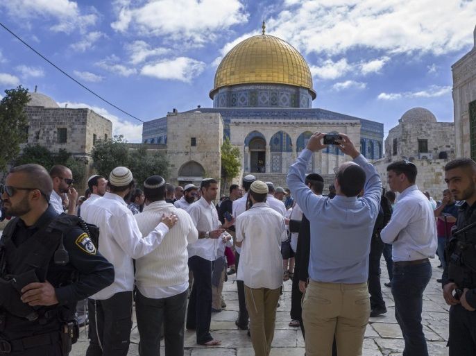 A group of right-wing Jews stop to look at the distinctive golden Dome of the Rock during a tour of the Temple Mount, or Harim el-Sharif (The Noble Sanctuary), in Jerusalem's Old City, 28 April 2016, during the Passover holiday. They are accompanied by Israeli police and riot police as well as by members of a Palestinian Al-Aqsa watch group who photograph each group of right-wing Jewish visitors, making sure they do not pray in the area during their visits.
