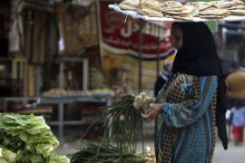 A woman with a tray of bread on her head, buys vegetables near a bakery in Cairo March 17, 2013. The spectre of steep food price inflation driven by a weaker pound is of particular worry to Egyptian President Mohamed Mursi as he grapples with spasms of unrest two years after the uprising that toppled Hosni Mubarak and was itself partly driven by a sense of mounting economic hardship in a country long steeped in poverty. REUTERS/Mohamed Abd El Ghany (EGYPT - Tags: POLITICS BUSINESS FOOD)