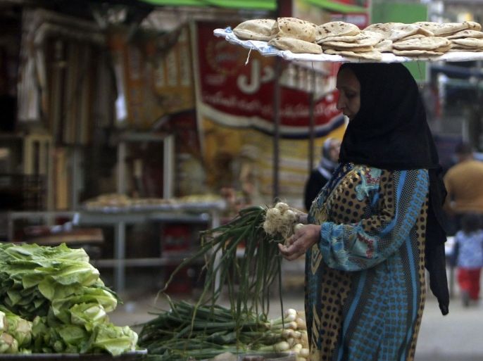A woman with a tray of bread on her head, buys vegetables near a bakery in Cairo March 17, 2013. The spectre of steep food price inflation driven by a weaker pound is of particular worry to Egyptian President Mohamed Mursi as he grapples with spasms of unrest two years after the uprising that toppled Hosni Mubarak and was itself partly driven by a sense of mounting economic hardship in a country long steeped in poverty. REUTERS/Mohamed Abd El Ghany (EGYPT - Tags: POLITICS BUSINESS FOOD)