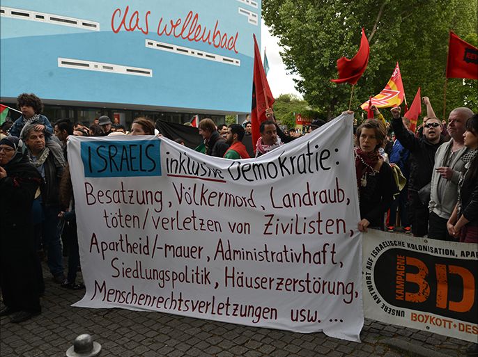 نشطاء من حركة المقاطعة الألمانية يرفعون لافتة تعدد جرائم وانتهاكات الاحتلال. الجزيرة نت