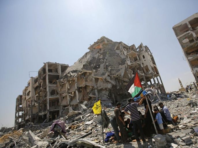 Palestinians sit in a makeshift tent next the rubble of the destroyed Al-Nada towers in Beit Lahia town in the northern Gaza Strip, 11 August 2014. A new, Egyptian-brokered 72-hour truce between Israel and armed groups in Gaza was holding. The Gaza death toll after more than a month of fighting has topped 1,900, including 449 children, 243 women and 87 elderly men, the enclave's Health Ministry said. An estimated 10,000 have been wounded.