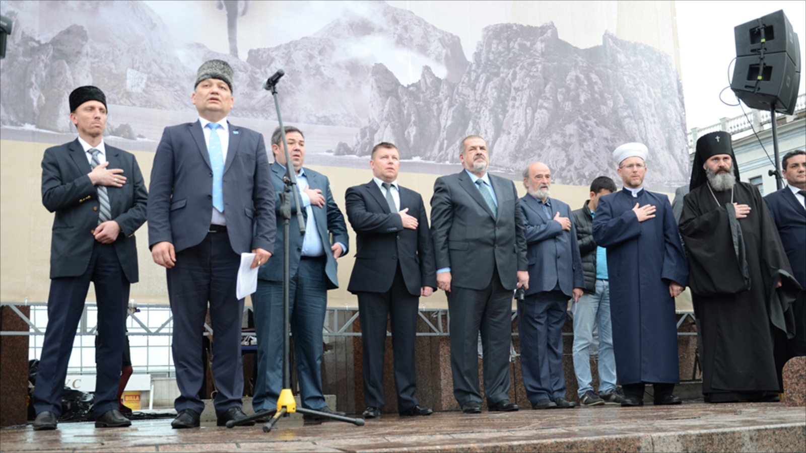 مسؤولون ورموز اجتماعية ودينية أثناء عزف النشيدين الوطنيين الأوكراني والتتري خلال إحياء ذكرى تهجير تتار القرم (الجزيرة نت)