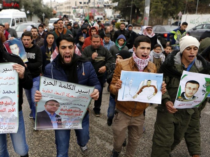 Palestinians hold posters bearing a portrait of Palestinian journalist Mohammed Al-Qeeq during a protest in solidarity with his health condition in the West Bank city of Hebron, 29 February 2016. Al-Qeeq is on a hunger strike for 66 days as a protest against his arrest without charges. The detention was done under Israel's controversial administrative detention law, which allows the state to hold suspects for renewable six-month periods without trial and he has been refusing food since November 25.