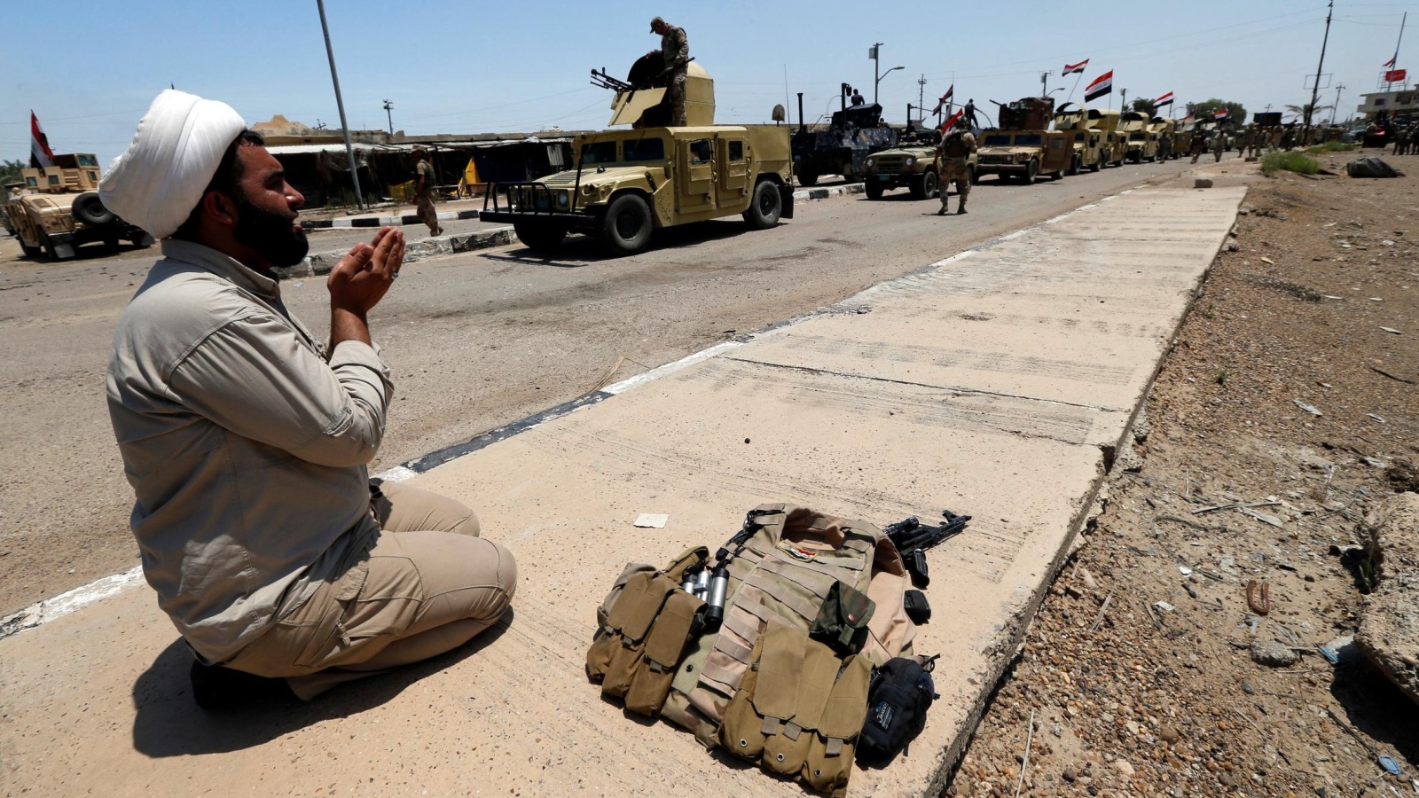 جندي من المليشيات الشيعية يصلي شكرا بعد دخول بلدة الكرمة (رويترز)