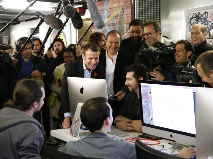 Journalists surround Xavier Niel (C), founder of French broadband Internet provider Iliad, French Economy Minister Emmanuel Macron (L) and Kwame Yamgnane (R) visit the 42 school campus in Paris, France, October 27, 2015. The French school 42, a private French computer programming school, was created and funded by Xavier Niel. REUTERS/Benoit Tessier