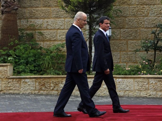 French Prime Minister Manuel Valls (C) and Palestinian Prime Minister Rami Hamdallah (L) inspect a guard of honour upon his arrival for a visit to the West Bank town of Ramallah, 24 May 2016. Valls was on a three-day visit to Israel.