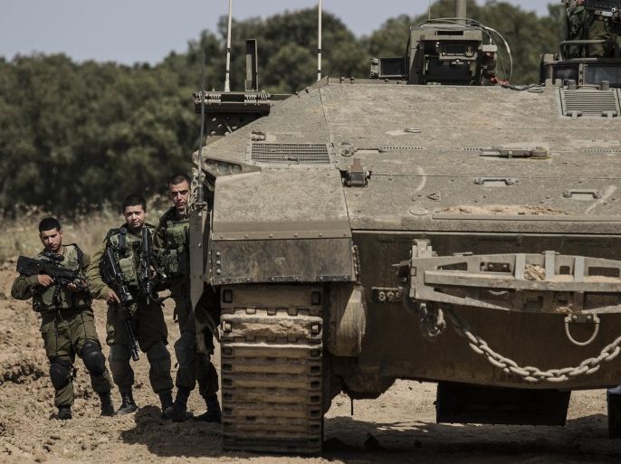 Israeli soldiers stand by a tank near the Israel Gaza border, Wednesday, May 4, 2016. The Israeli army says a tank has fired at a target in the northern Gaza Strip following an explosion on the Palestinian side of the border. The army says it's trying to determine the source of the explosion, which took place on Wednesday. Earlier, a tank fired into Gaza after a mortar shell was launched toward Israeli forces near the southern Gaza Strip. (AP photo/Tsafrir Abayov)