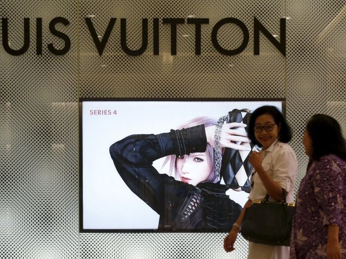 An Indonesian woman talks with her colleague as they walk past a Louis Vuitton shop at a mall in Jakarta, February 5, 2016. Business may be about to look up for the wealth-management industry helped by President Joko Widodo's tax amnesty plan that could encourage rich Indonesians to declare assets previously concealed from the authorities, either at home or abroad. Picture taken February 5, 2016. REUTERS/Beawiharta