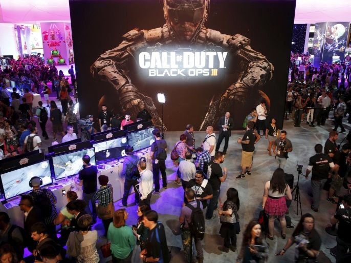 Attendees play Sony Playstation video games in front of a "Call of Duty: Black Ops 3" poster at the Electronic Entertainment Expo, or E3, in Los Angeles, California, United States, June 17, 2015. Virtual reality gaming, once a distant concept, became the new battleground at this year's E3 industry convention, with developers seeking to win over fans with their immersive headsets and accessories. REUTERS/Lucy Nicholson